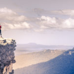 image of a woman standing on a cliff looking over hills