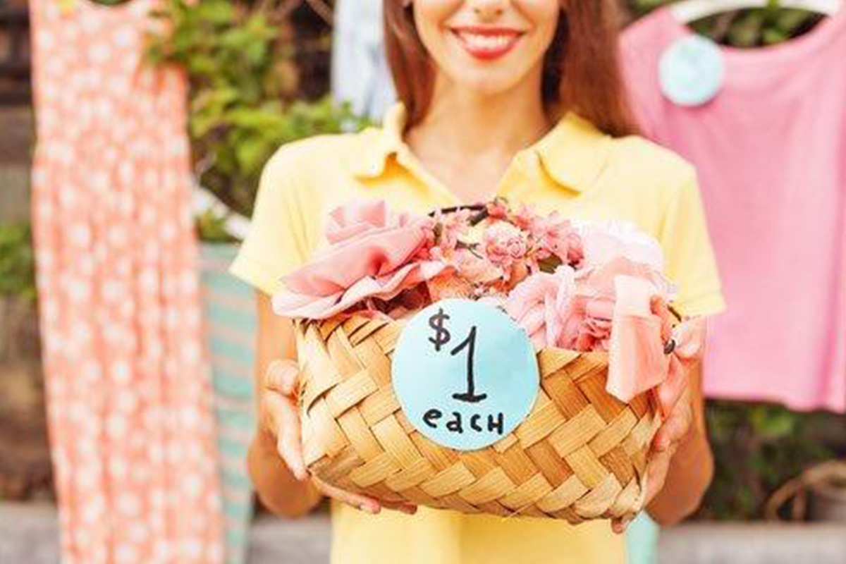 smiling woman holds out basket of items for sale for $1