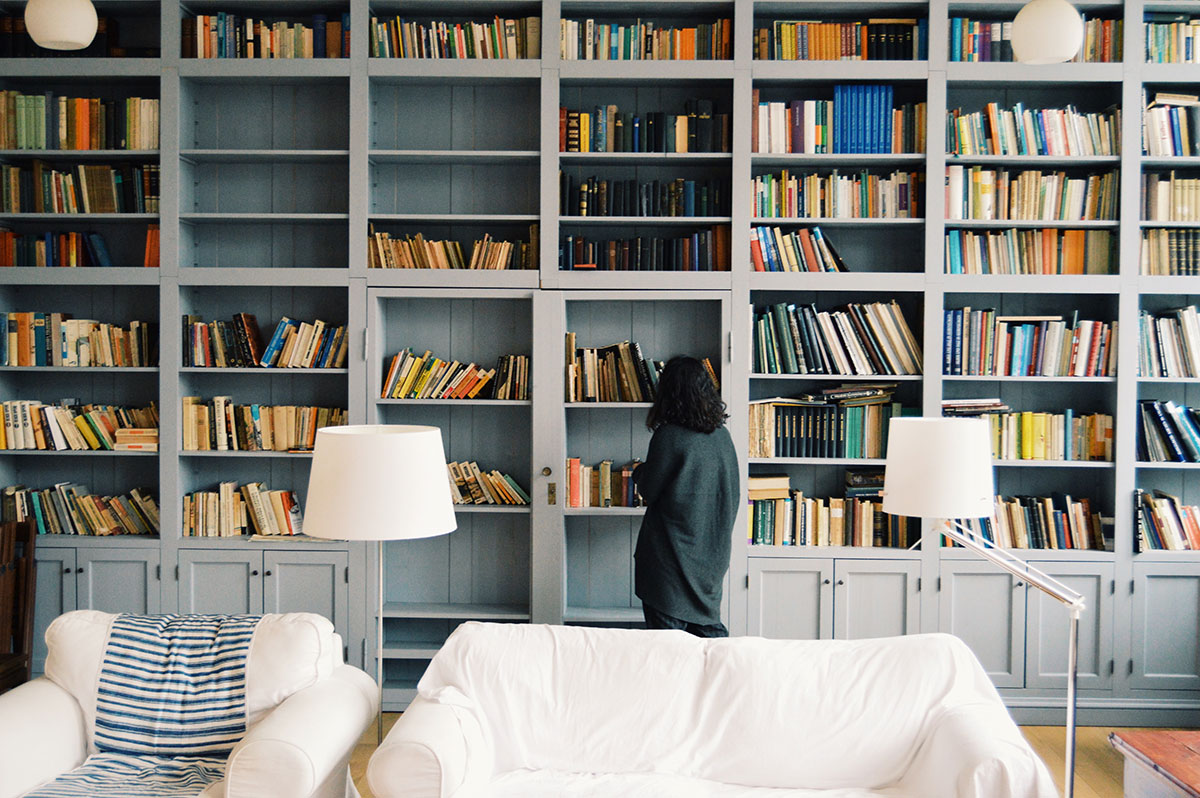 image of a girl looking up at a bookshelf that takes up the entire wall