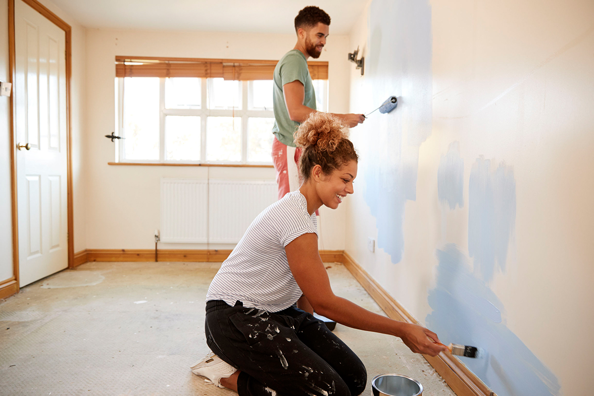 smiling young couple paints an interior wall together