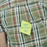 happy april fools day post it note on back of man's shirt