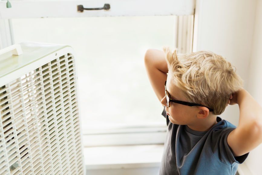 image of a boy cooling off in front of an old box fan on a hot summer day