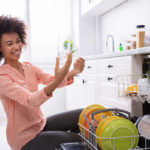 woman admires clean glasses removed from dishwasher