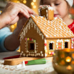 father and daughter build a gingerbread house