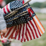 woman walks with armful of small American flags