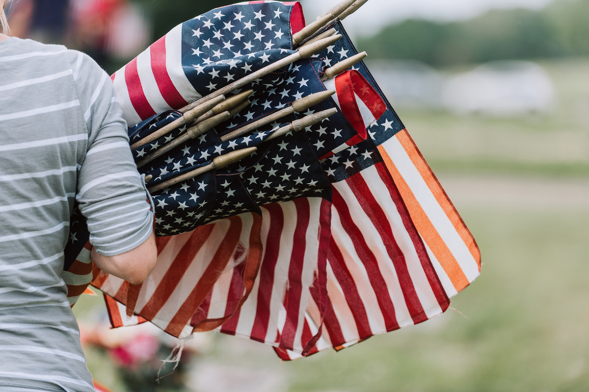 woman walks with armful of small American flags