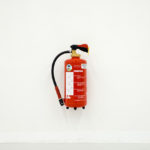 image of a fire extinguisher hanging on a bare white wall