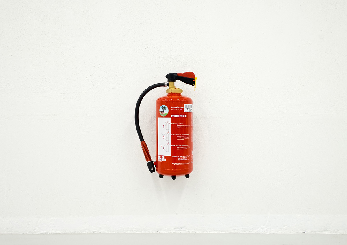 image of a fire extinguisher hanging on a bare white wall