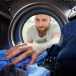young man reaches into dryer for clothing