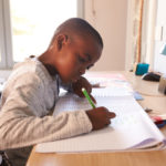 young boy doing homework at a desk
