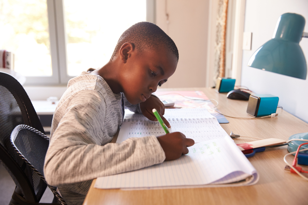young boy doing homework at a desk