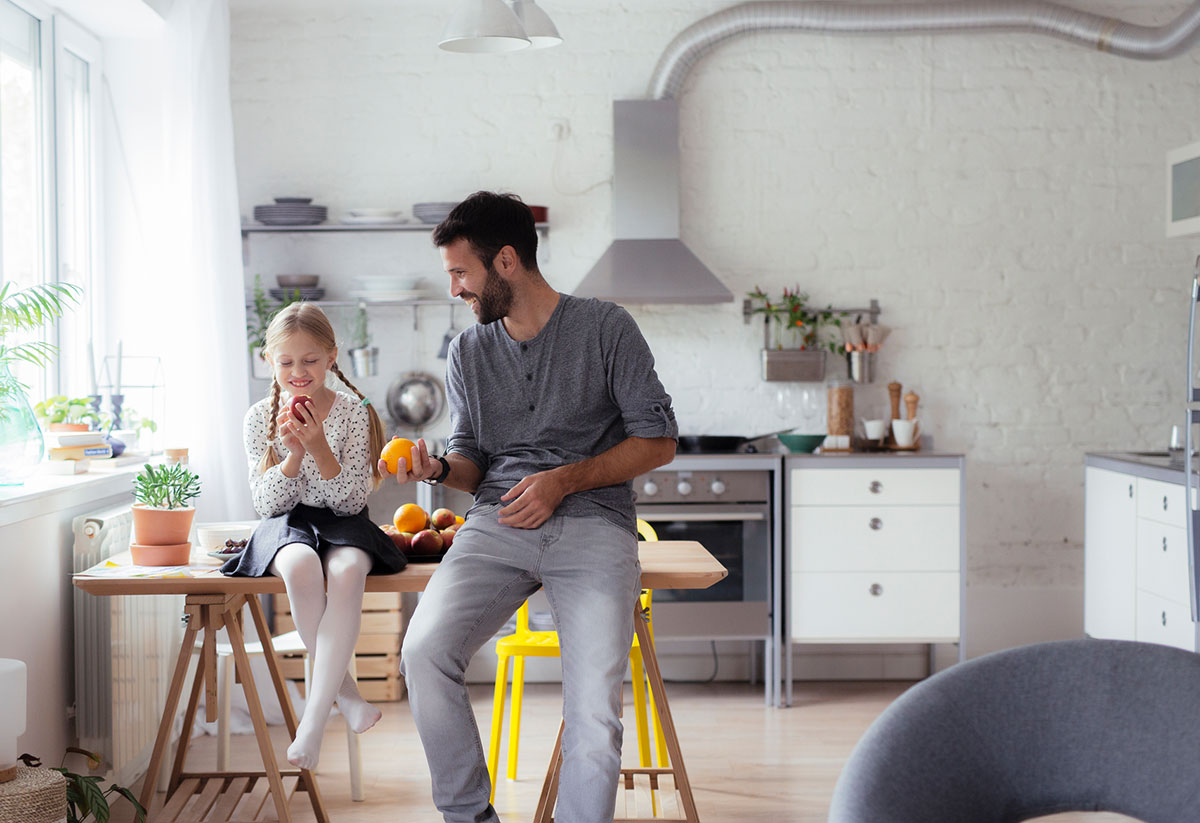 image of a father and his young daughter sitting on the kitchen table while laughing