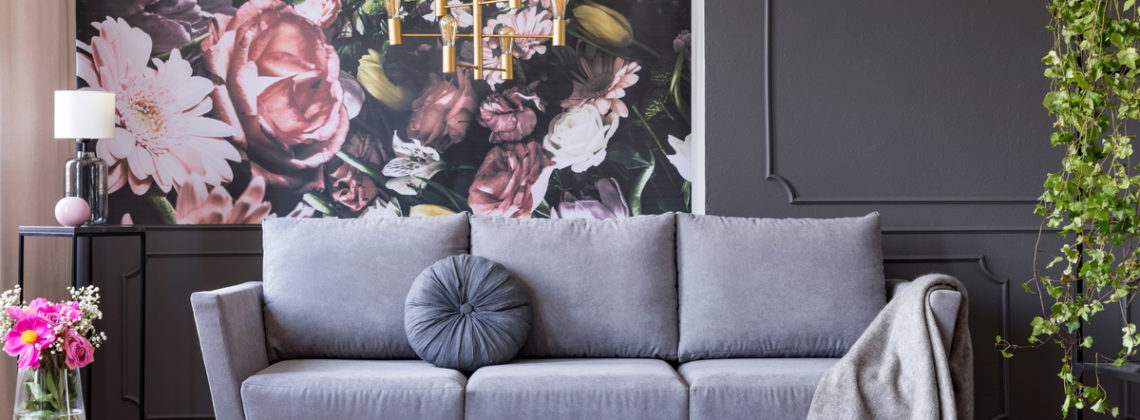 a living room with a gray couch and a floral wallpaper