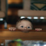 toddler looks over the edge of table