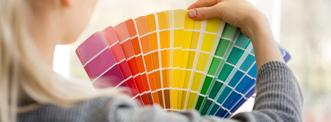 woman holds up colorful paint samples