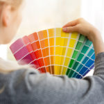 woman holds up colorful paint samples