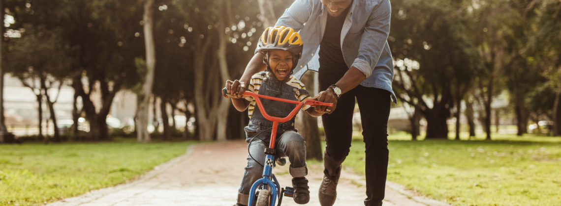 young father teaches son to ride a bicycle