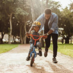 young father teaches son to ride a bicycle