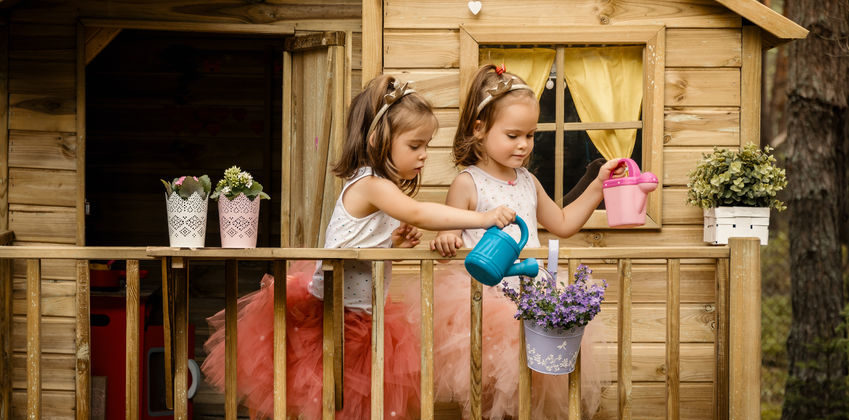 Two girls play with watering can in a tree house