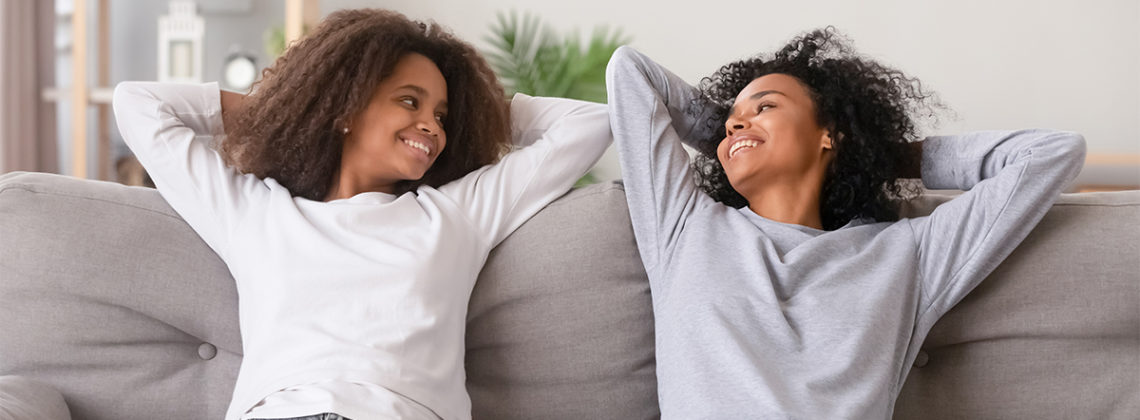 mother and daughter relax and smile on couch
