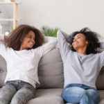 mother and daughter relax and smile on couch