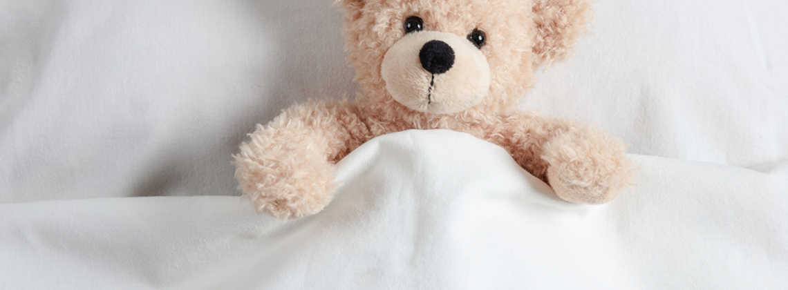 teddy bear tucked in a blanket