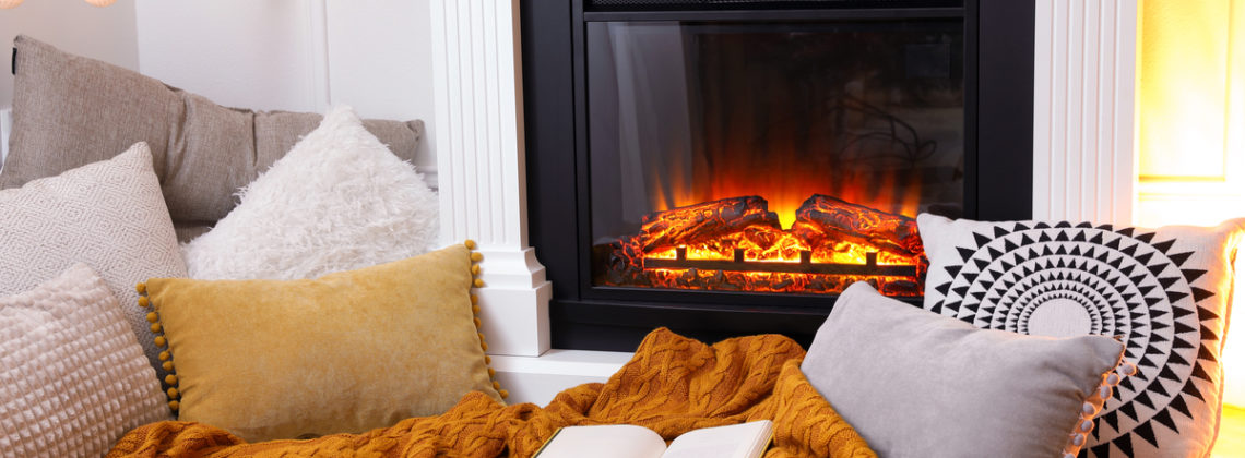 cozy blanket and pillows in front of electric fireplace