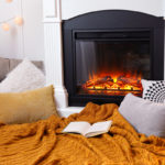 cozy blanket and pillows in front of electric fireplace