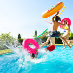 kids jumping into a pool with pool noodles and floaters