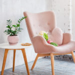 pink upholstered chair with heart-shaped pillow and bouquet of flowers