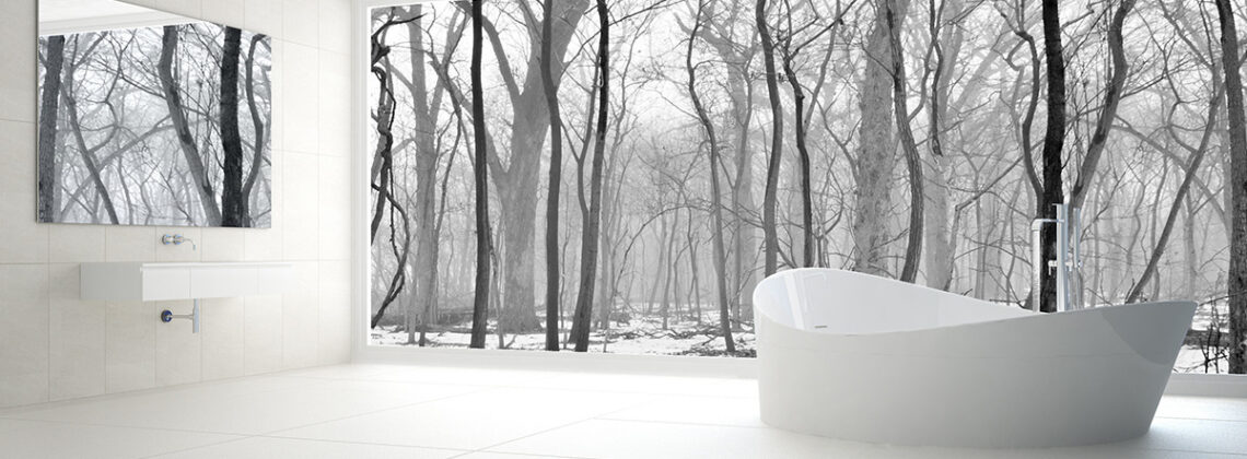 white bathtub faces out a window over a snowy yard and winter trees