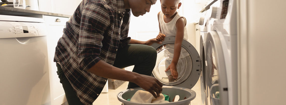 father and young son pull clothes from dryer