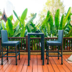 modern patio furniture sits on top of deck with plants in background