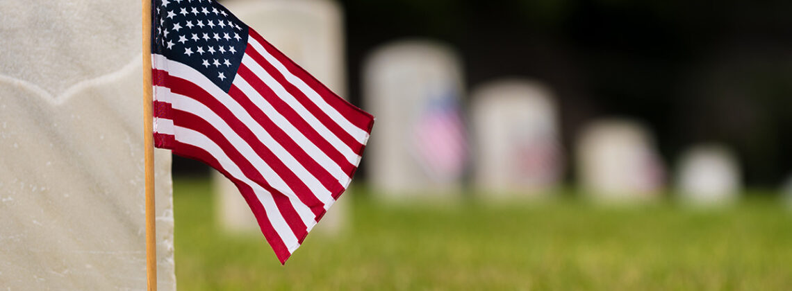 close up of small american flag on a military grave in a cemetery