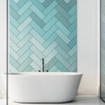 modern white bathtub in front of aqua colored wall tiles
