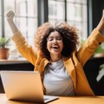 Woman in front of her laptop expressing victory