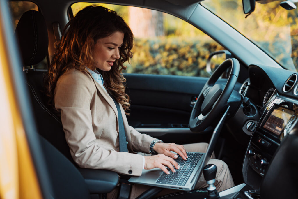 woman in her car doing business on a laptop