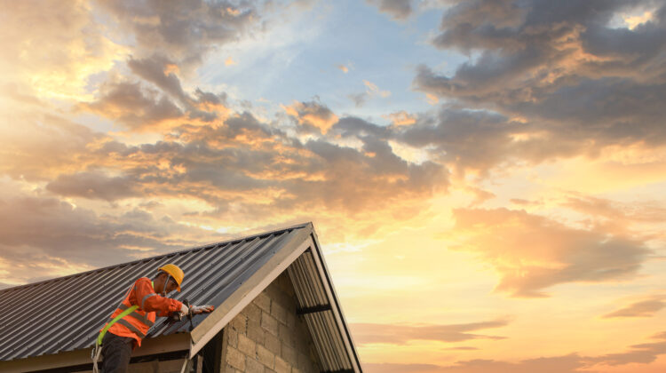worker on a roof with sunset in the background