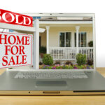 house with laptop and for sale sign
