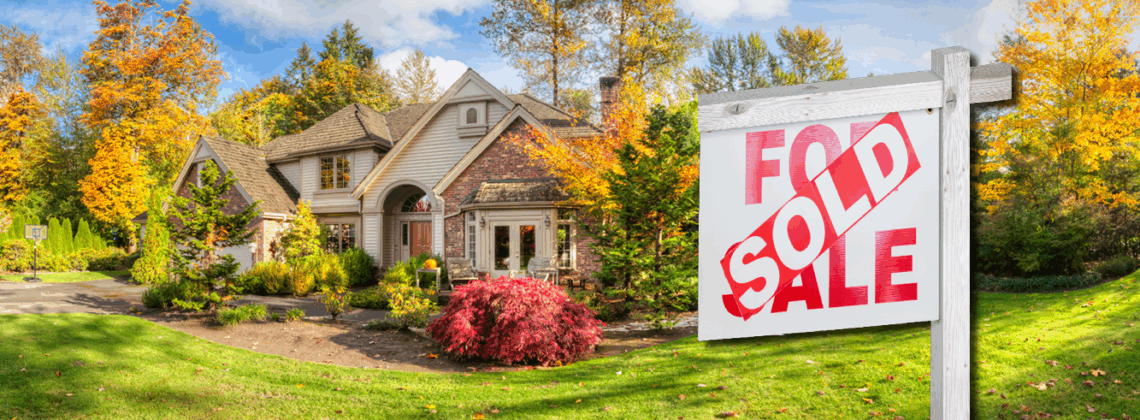 Nice home surrounded by fall colors and a for sale real estate sign