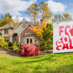 Nice home surrounded by fall colors and a for sale real estate sign