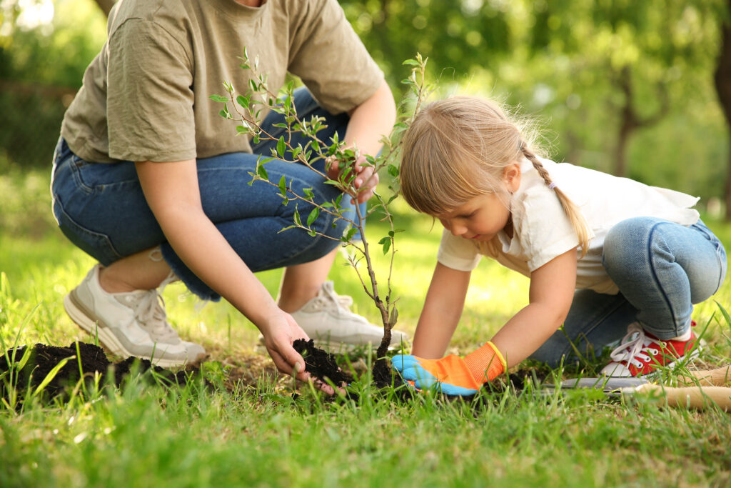 mom and daughter planting a tree