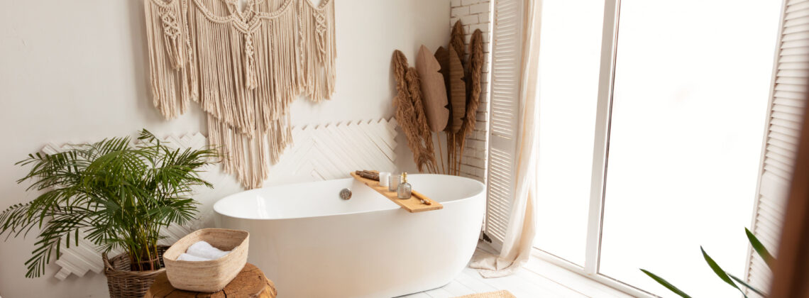 contemporary white bathtub in front of a window with plants and macrame hangings