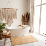 contemporary white bathtub in front of a window with plants and macrame hangings