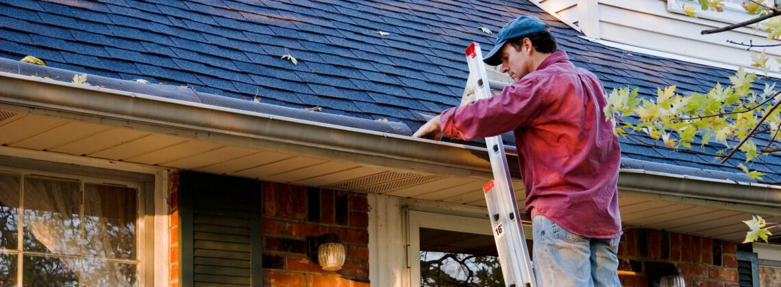 Man Cleaning Gutters on Ladder